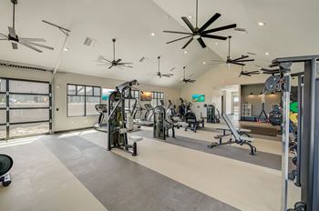 A gym with weights machines and ceiling fans
